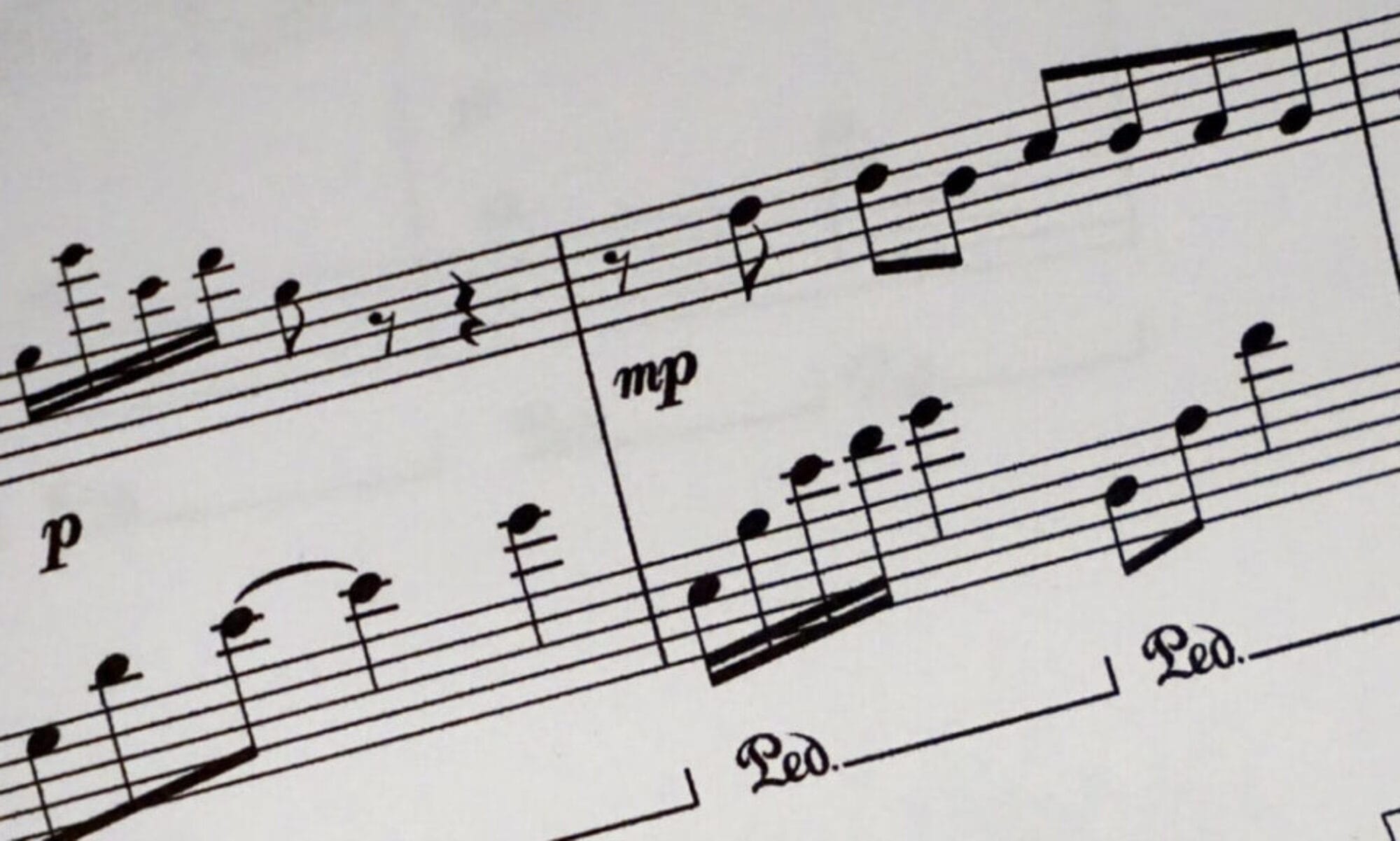 Header background showing printed sheet music showing staves, musical notes, dynamics, and pedal markings